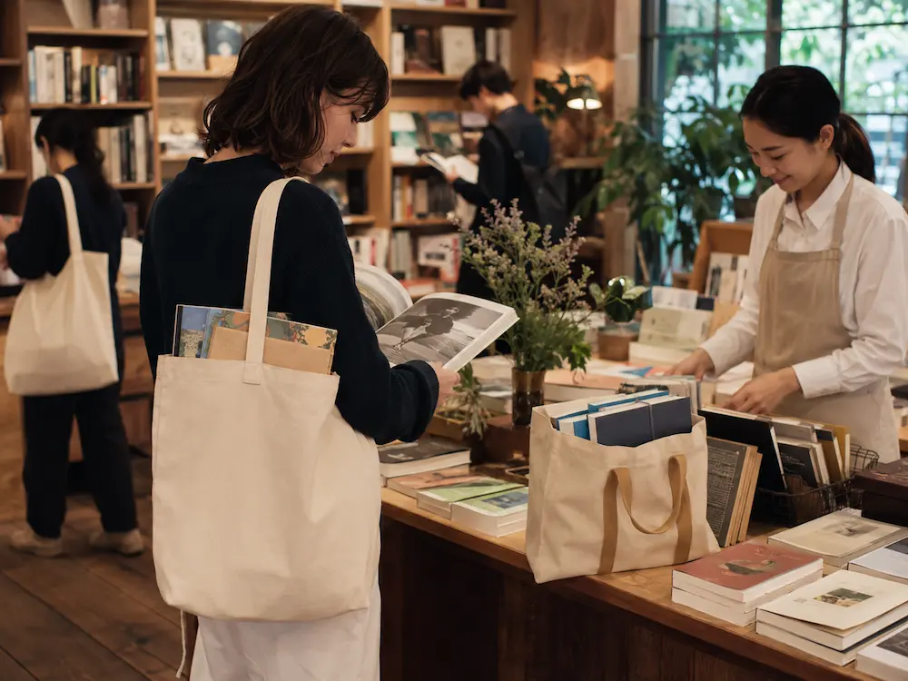 Reusable cotton and canvas tote bags used in a modern bookstore for carrying books and promoting sustainable retail